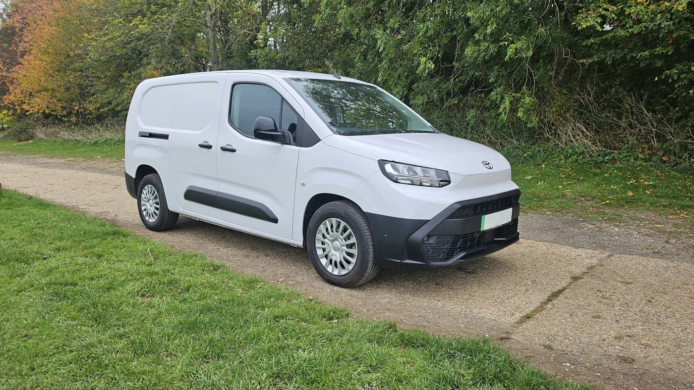 White delivery van parked beside a tree-lined road